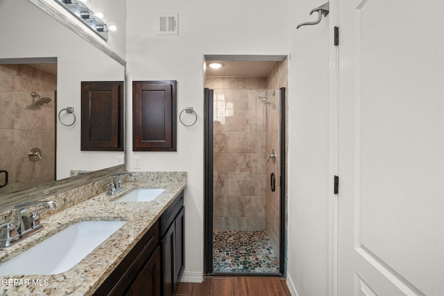 bathroom with wood-type flooring, vanity, and a shower with shower door