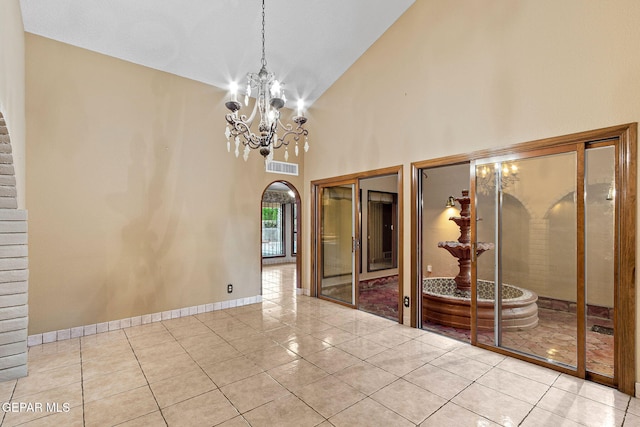 empty room featuring a notable chandelier, light tile patterned flooring, and high vaulted ceiling