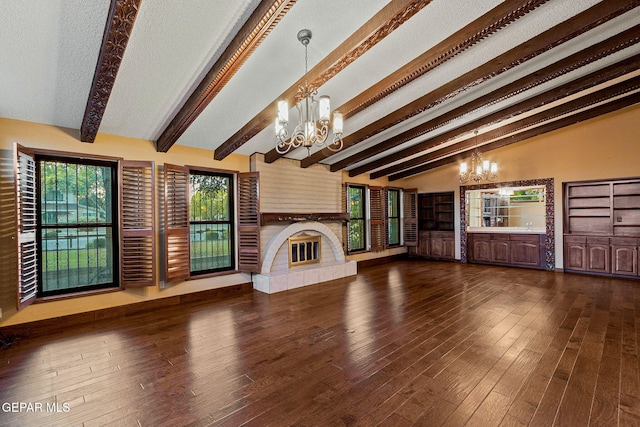 unfurnished living room with dark hardwood / wood-style flooring, a textured ceiling, a tile fireplace, lofted ceiling with beams, and a notable chandelier