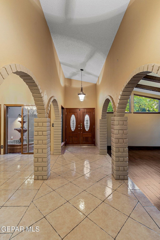 entryway with light hardwood / wood-style flooring, high vaulted ceiling, and a textured ceiling