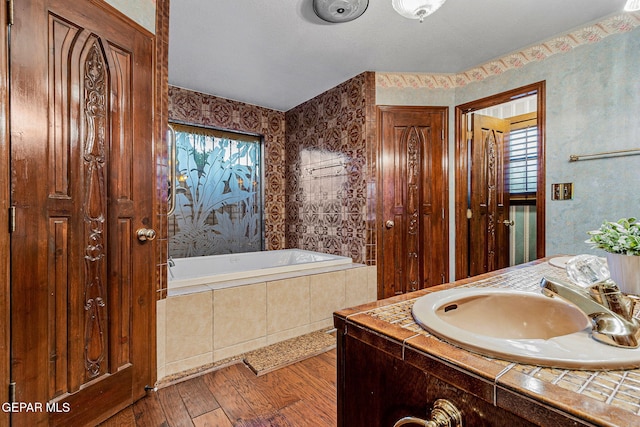 bathroom featuring vanity, a relaxing tiled tub, and hardwood / wood-style flooring