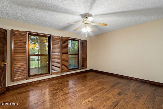 empty room with a wealth of natural light, dark hardwood / wood-style flooring, ceiling fan, and a textured ceiling