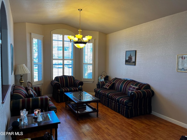 living room featuring vaulted ceiling, dark hardwood / wood-style floors, and an inviting chandelier