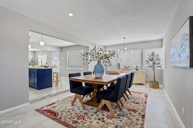 dining area with a textured ceiling, sink, and an inviting chandelier