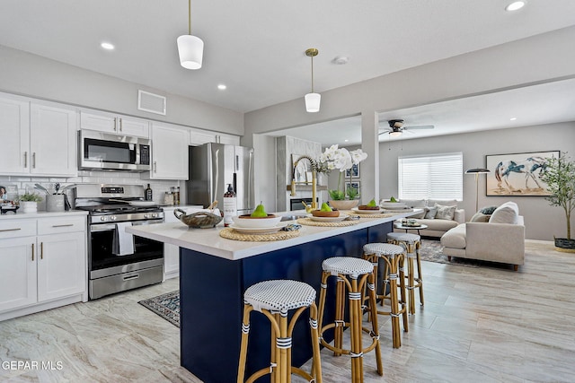 kitchen with stainless steel appliances, tasteful backsplash, a kitchen breakfast bar, hanging light fixtures, and white cabinets