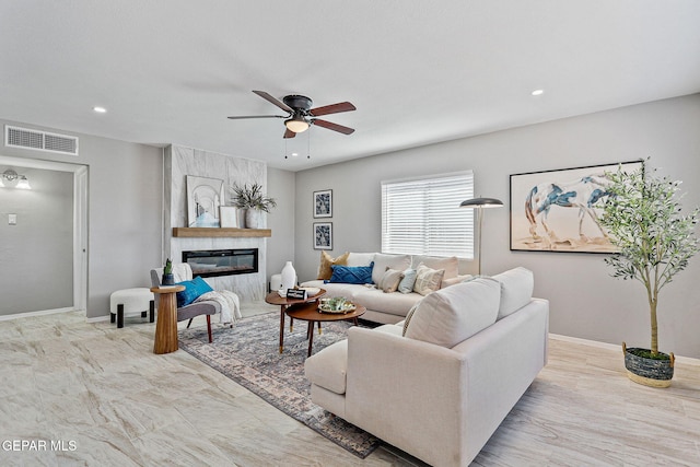 living room featuring a premium fireplace and ceiling fan