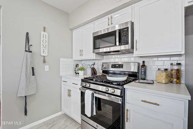 kitchen featuring stainless steel appliances, white cabinetry, backsplash, and light wood-type flooring