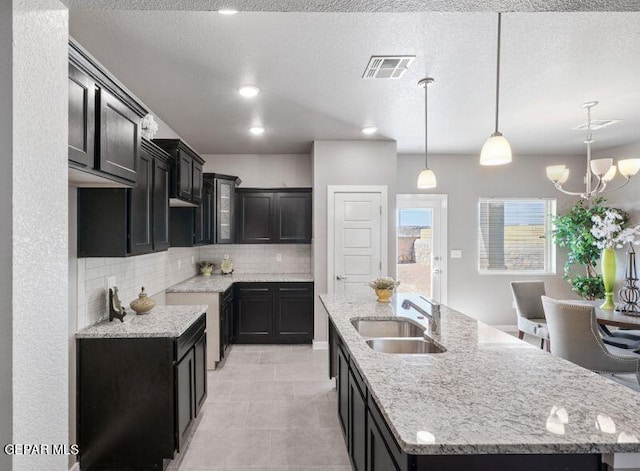 kitchen featuring a chandelier, sink, hanging light fixtures, and an island with sink