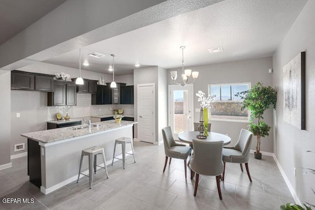 tiled dining space with a chandelier, a textured ceiling, and sink