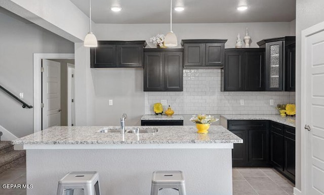 kitchen with a breakfast bar area, sink, an island with sink, and hanging light fixtures