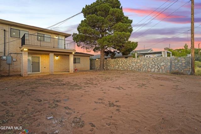 yard at dusk featuring a balcony