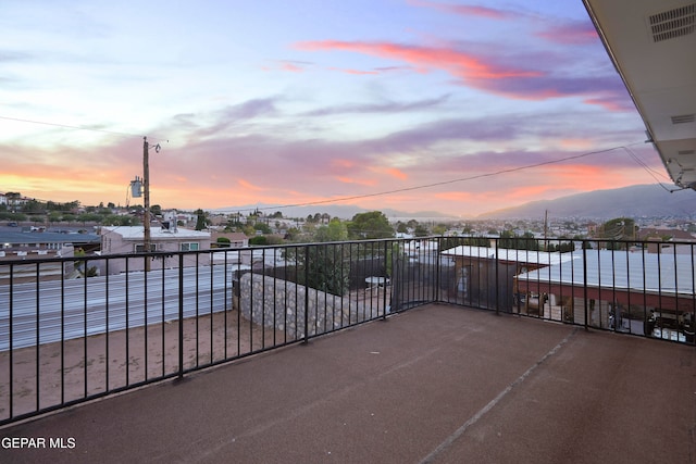 patio terrace at dusk with a mountain view and a balcony