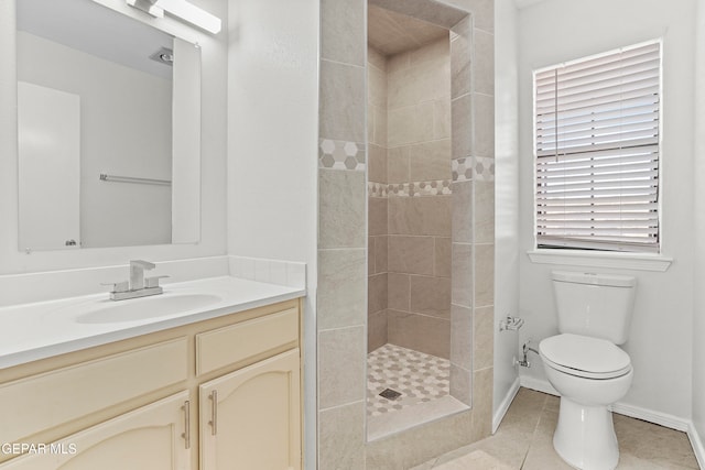 bathroom with a tile shower, tile patterned floors, vanity, and toilet