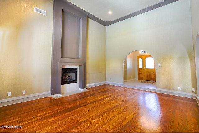 unfurnished living room with wood-type flooring and a towering ceiling