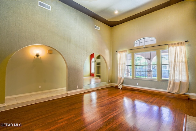 unfurnished living room with hardwood / wood-style flooring and a towering ceiling