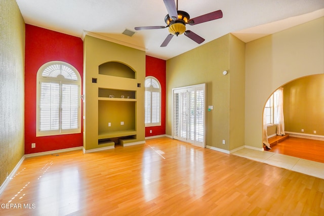 unfurnished living room with built in shelves, a wealth of natural light, and wood-type flooring