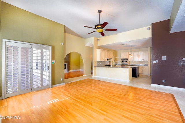 unfurnished living room with light wood-type flooring, ceiling fan, and vaulted ceiling