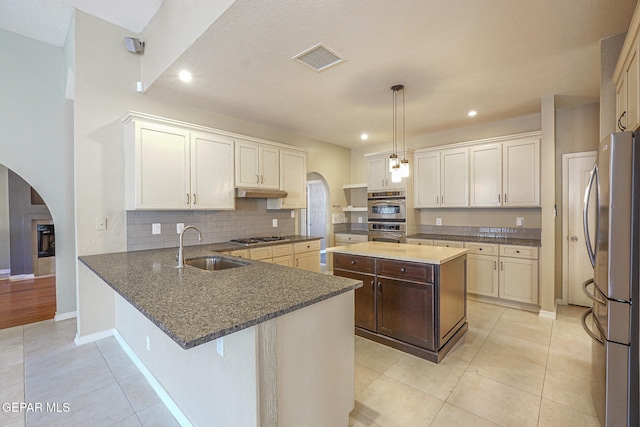 kitchen with appliances with stainless steel finishes, decorative light fixtures, sink, a kitchen breakfast bar, and kitchen peninsula