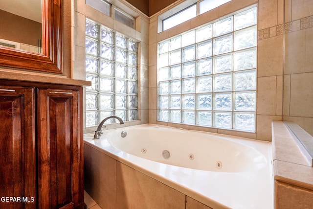 bathroom featuring a wealth of natural light and tiled tub