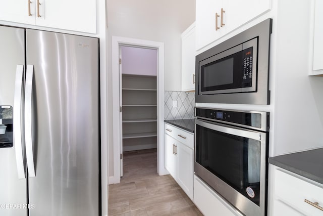 kitchen featuring white cabinets, backsplash, light hardwood / wood-style floors, and stainless steel appliances