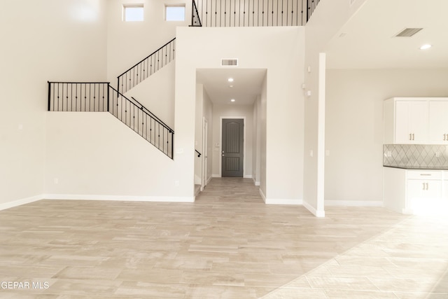 foyer entrance featuring light hardwood / wood-style flooring and a high ceiling