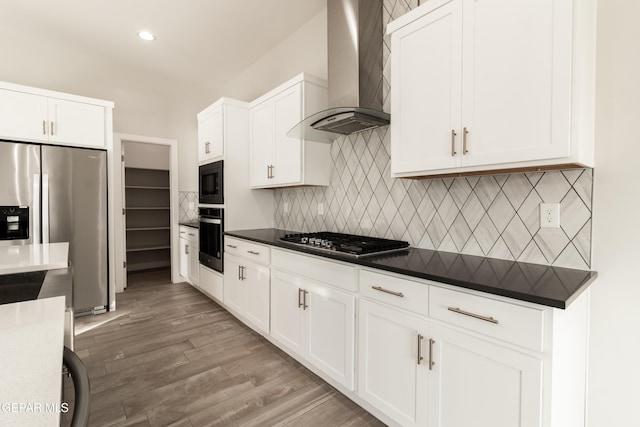 kitchen featuring decorative backsplash, wall chimney exhaust hood, stainless steel appliances, light hardwood / wood-style floors, and white cabinetry