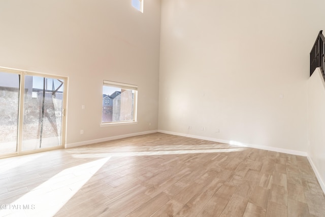 unfurnished living room featuring a high ceiling and light wood-type flooring