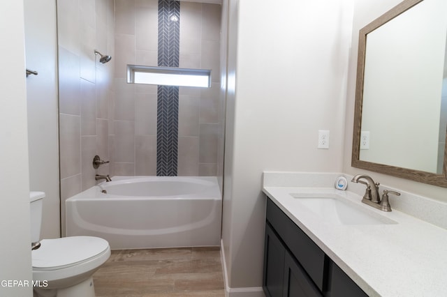 full bathroom with hardwood / wood-style floors, vanity, tiled shower / bath combo, and toilet