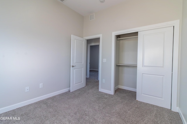 unfurnished bedroom featuring light carpet and a closet