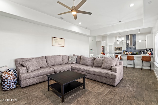 living room featuring ceiling fan with notable chandelier and dark hardwood / wood-style flooring