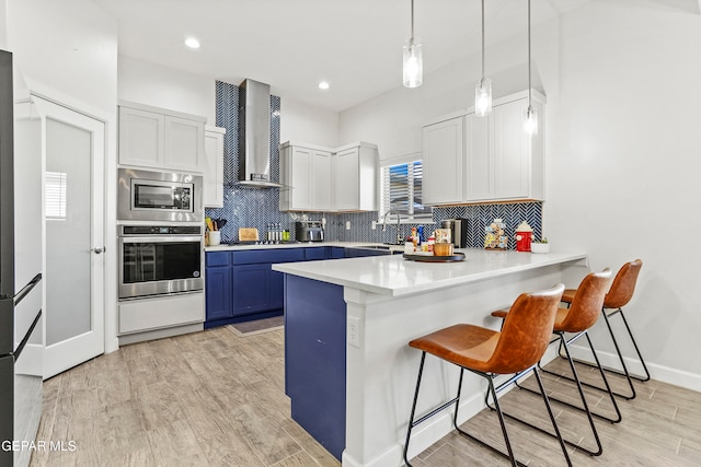 kitchen featuring white cabinets, light hardwood / wood-style floors, wall chimney range hood, and blue cabinets