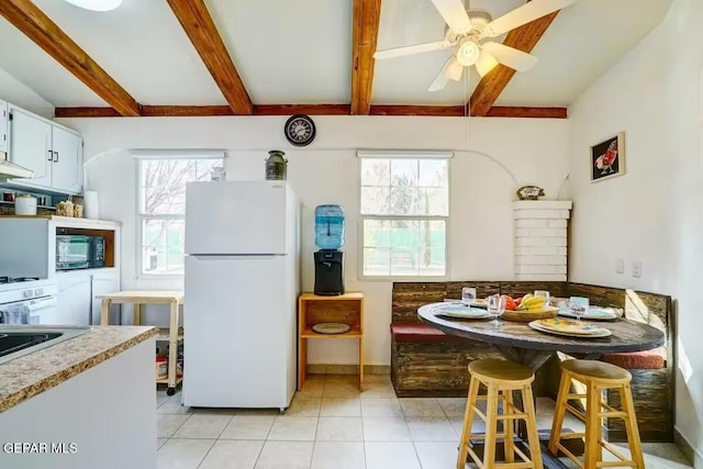 kitchen with beamed ceiling, plenty of natural light, white cabinets, white refrigerator, and breakfast area