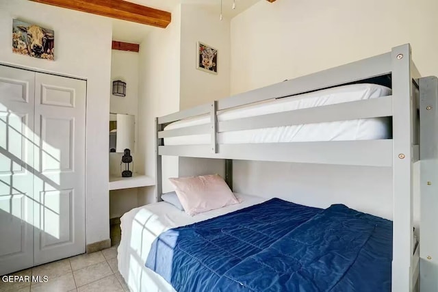 bedroom with light tile patterned floors and beam ceiling