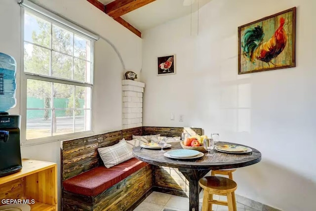 interior space with breakfast area, light tile patterned floors, and beamed ceiling