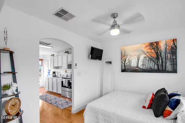 bedroom with ceiling fan, ensuite bathroom, and light hardwood / wood-style floors