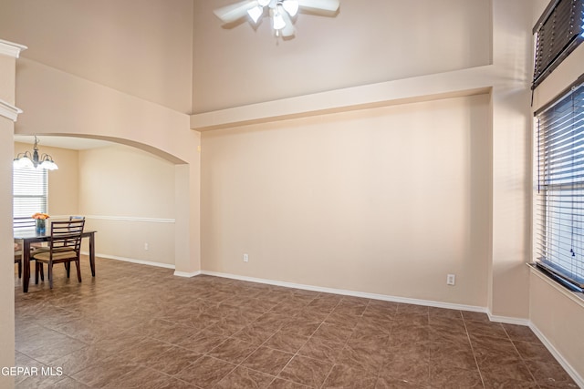 unfurnished room featuring a towering ceiling and ceiling fan with notable chandelier