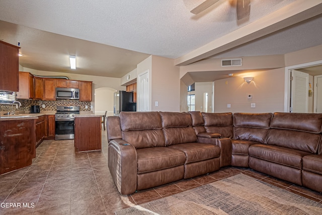 living room featuring a textured ceiling, dark tile patterned floors, ceiling fan, and sink