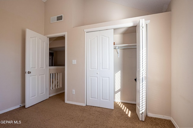 unfurnished bedroom featuring carpet, vaulted ceiling, and a closet