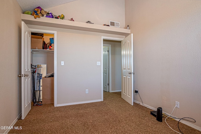 unfurnished bedroom featuring a textured ceiling, carpet floors, and vaulted ceiling