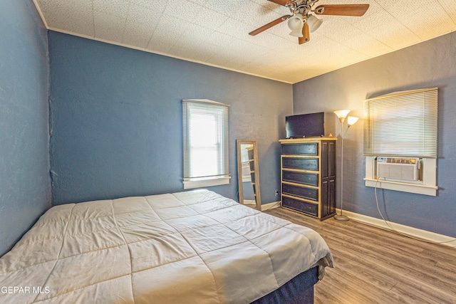 bedroom featuring hardwood / wood-style floors, ceiling fan, and cooling unit