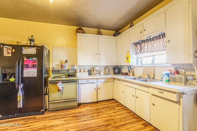 kitchen featuring white cabinets, black fridge, stainless steel range with electric cooktop, and sink