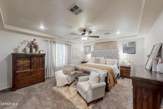 carpeted bedroom featuring a tray ceiling and ceiling fan