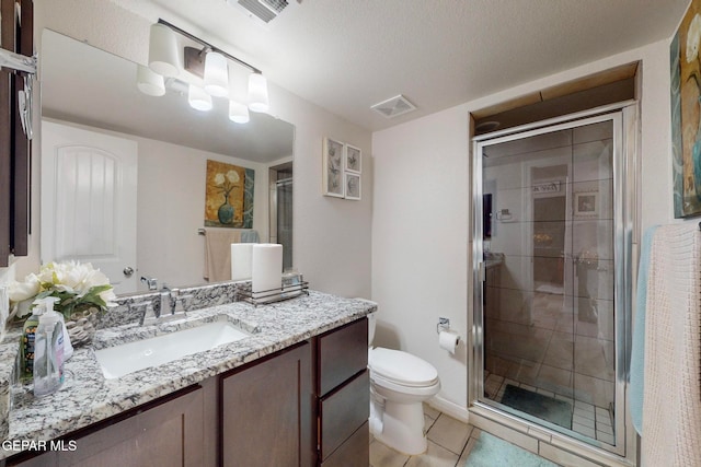 bathroom featuring tile patterned floors, a textured ceiling, toilet, a shower with door, and vanity