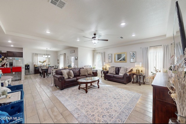 living room with ceiling fan with notable chandelier, a textured ceiling, and light hardwood / wood-style flooring