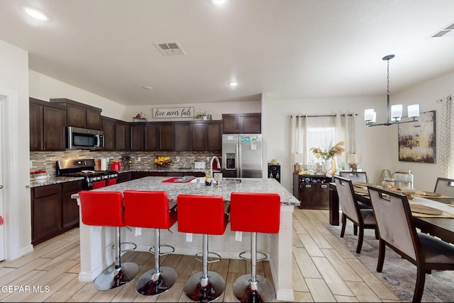 kitchen with an island with sink, stainless steel appliances, and light wood-type flooring