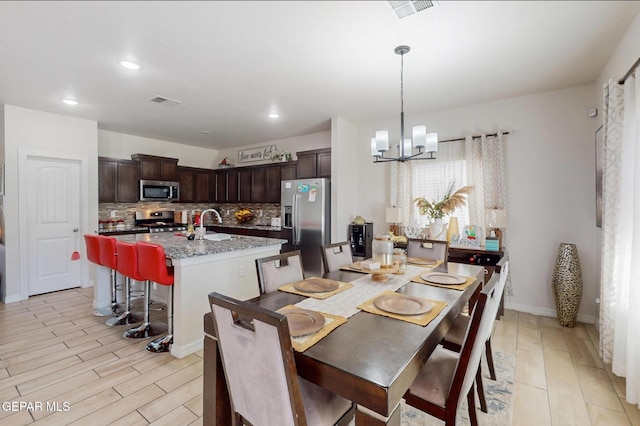 dining room featuring light hardwood / wood-style floors, a notable chandelier, and sink