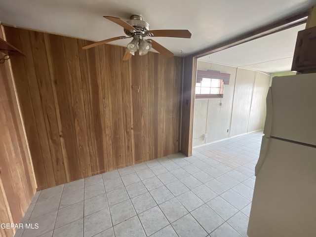 kitchen with ceiling fan, white fridge, light tile patterned flooring, and wooden walls