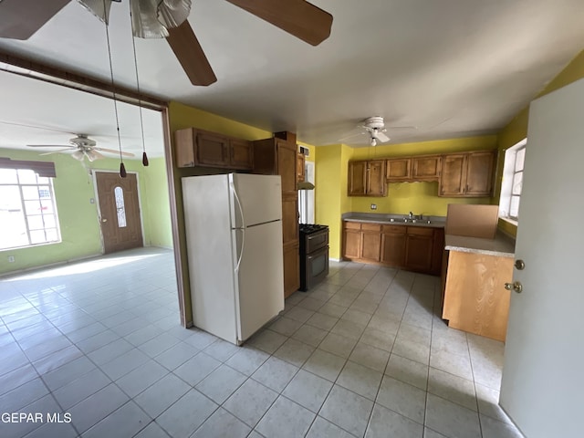 kitchen featuring light tile patterned floors, white fridge, black range with gas cooktop, and sink