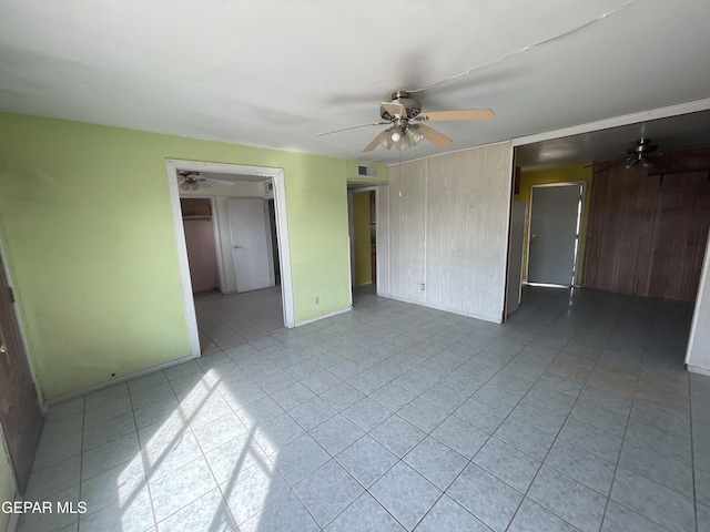 tiled spare room with wood walls and ceiling fan