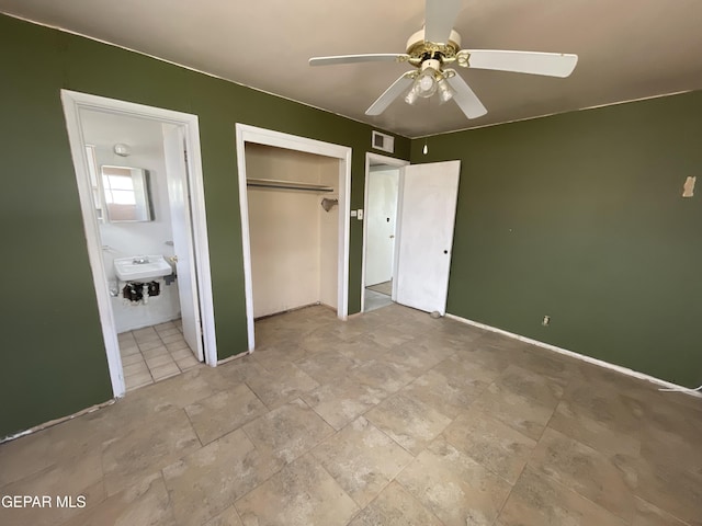 unfurnished bedroom featuring ensuite bathroom, ceiling fan, sink, and a closet